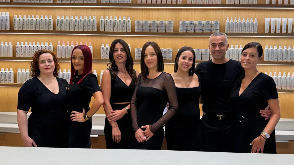 The I.C.O.N. team dressed in black behind the counter, in front of the lit retail wall