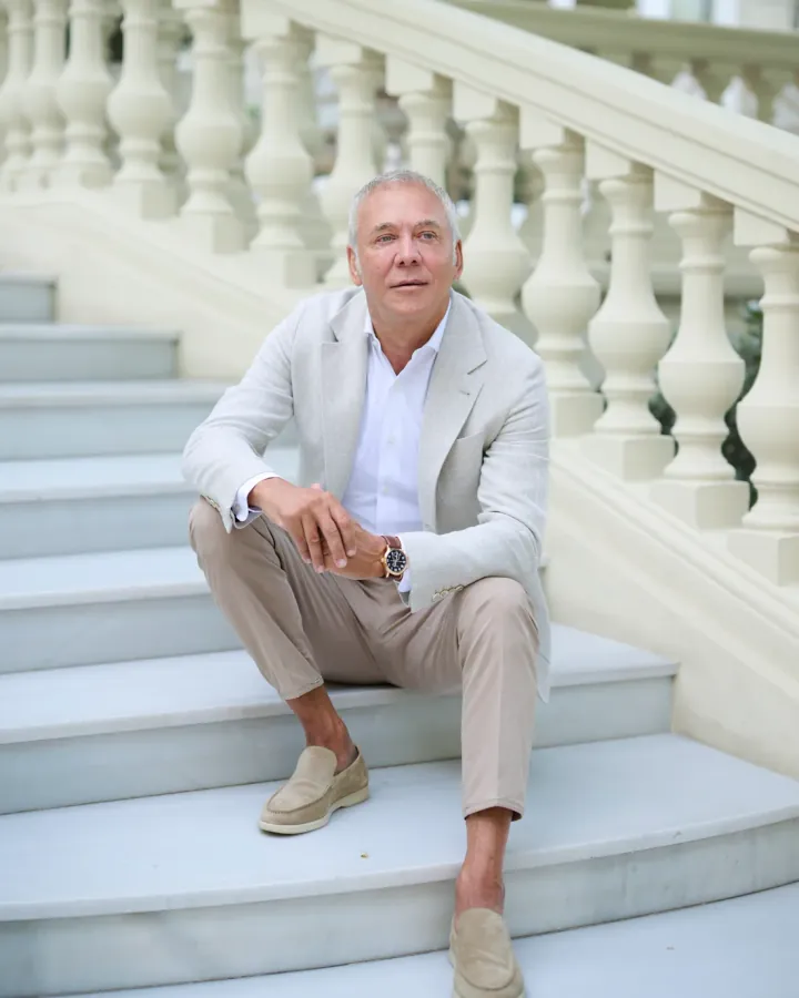 Jorge Rubín seated on the steps of a white balustraded staircase