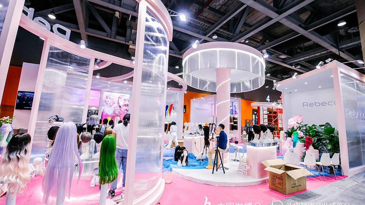 Wigs on display at a pink exhibitor stand on the China Hair Expo floor