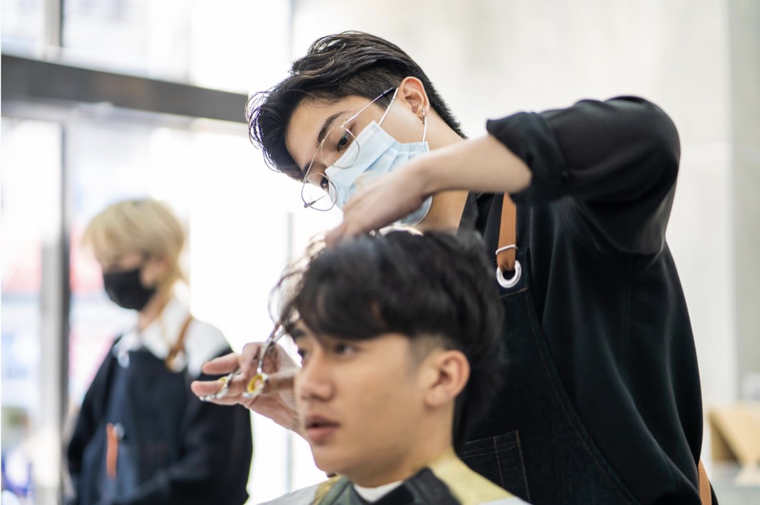 A stylist cutting a client's hair in an Asian salon