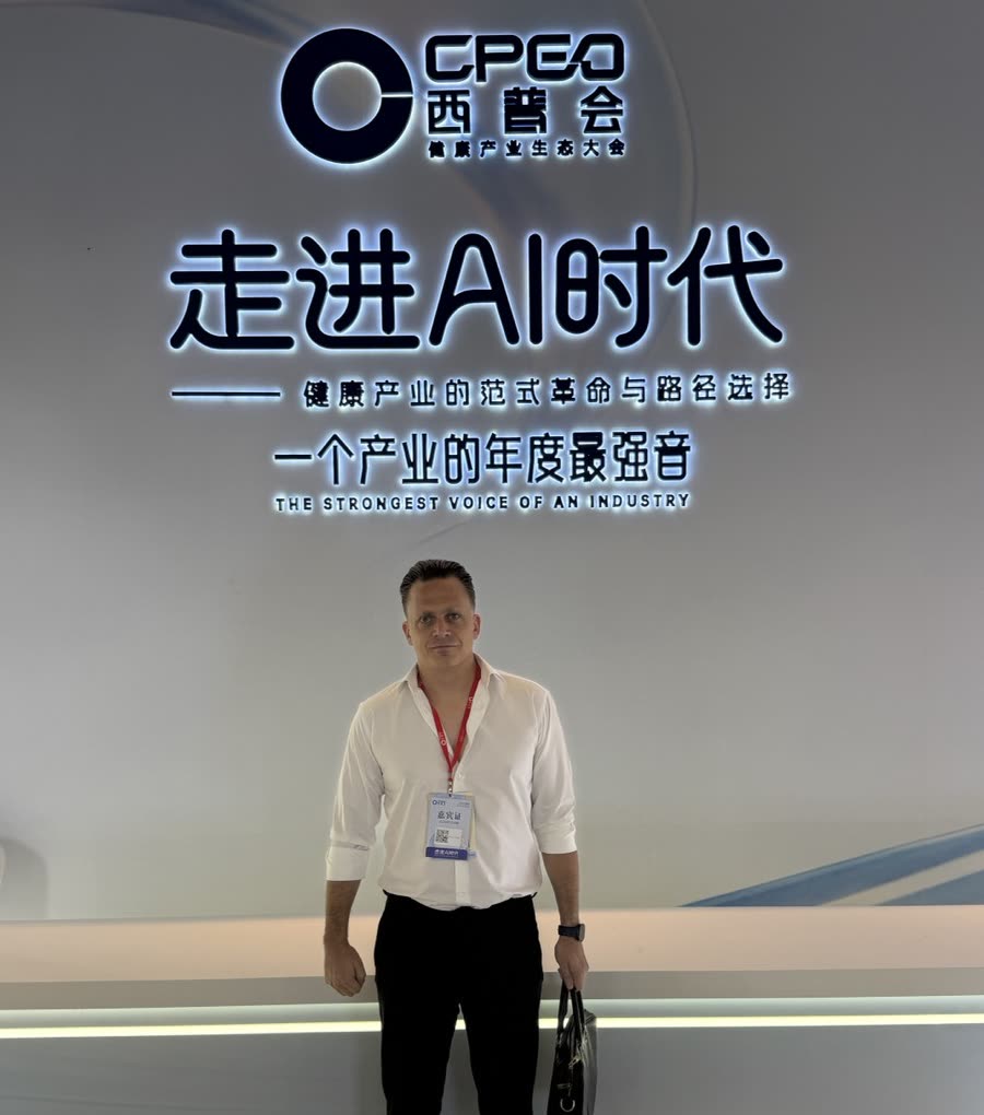 Kevin Maes on the stage floor at CPEO in Hainan, in front of the summit backdrop.